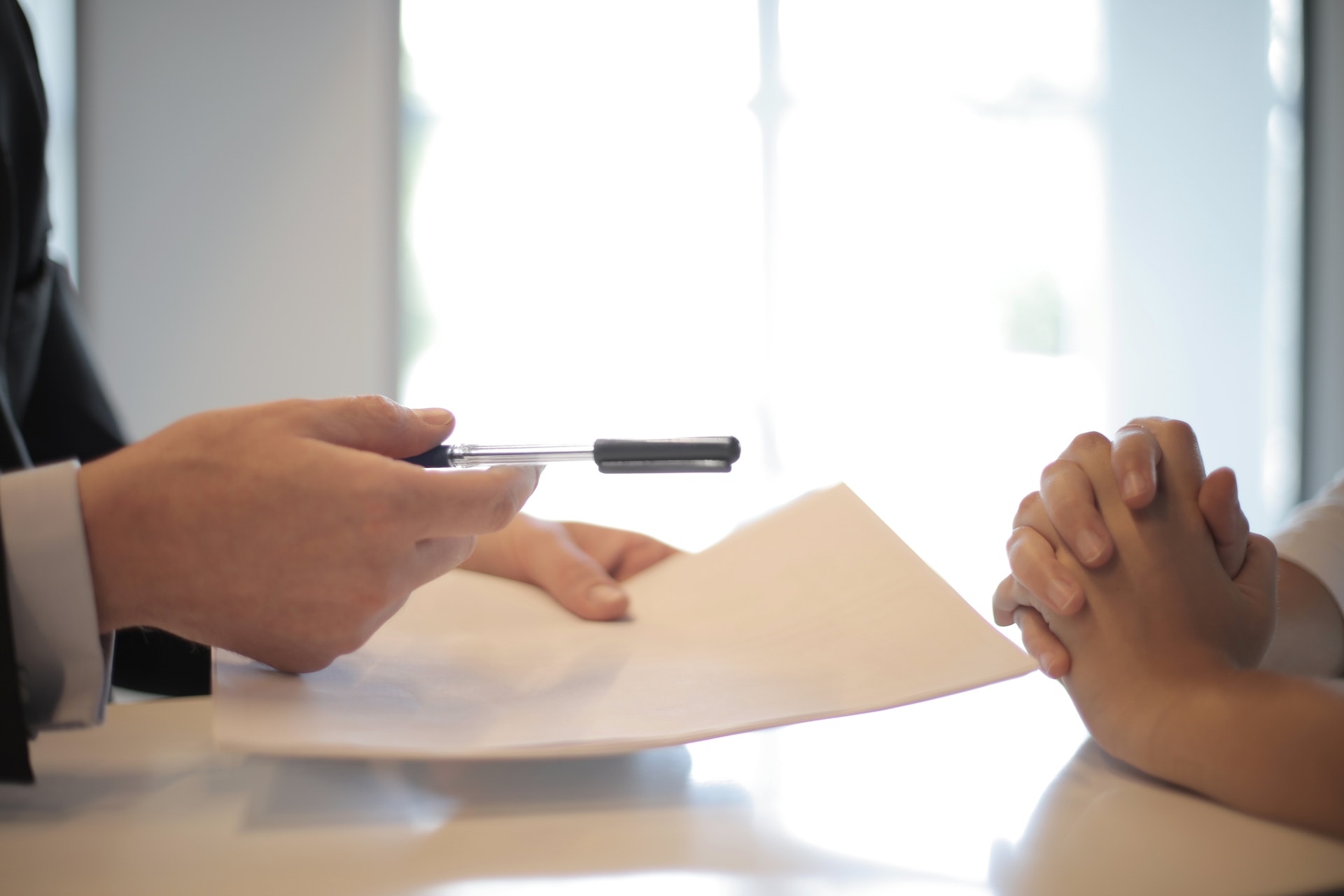 Man offers another person a pen to sign a form